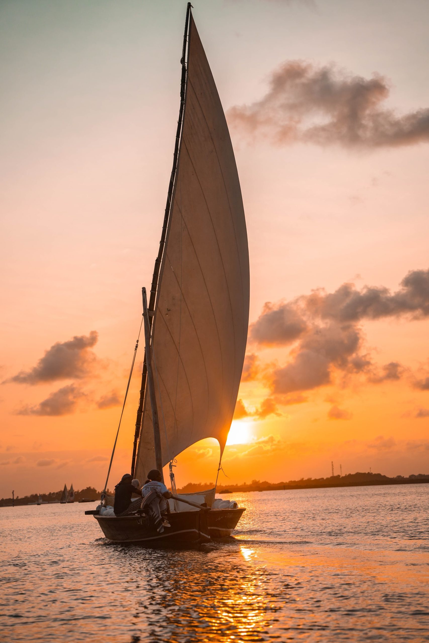 A sailboat glides on calm waters against a vibrant sunset, perfect for travel and adventure themes.