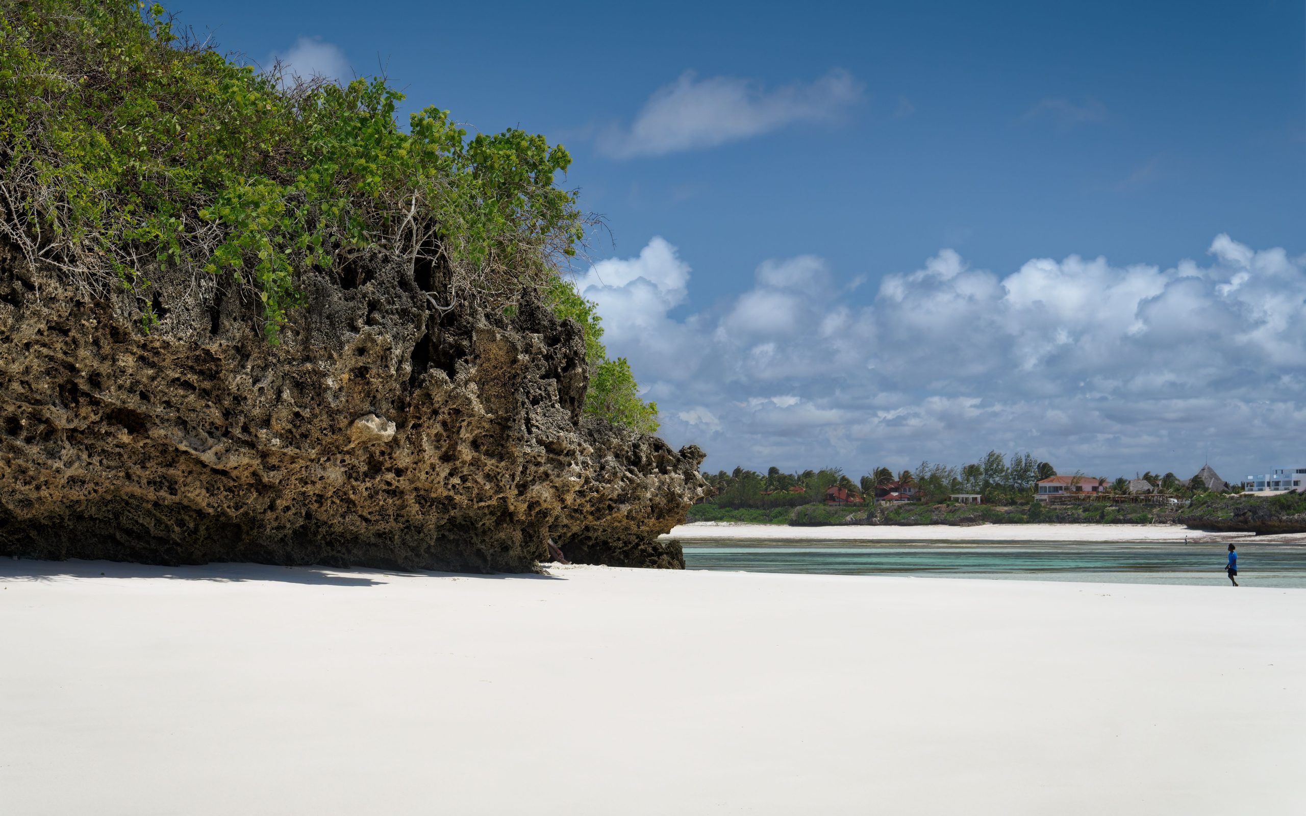 Tropical beach scene at Watamu, Kenya with clear skies and rocky shoreline.
